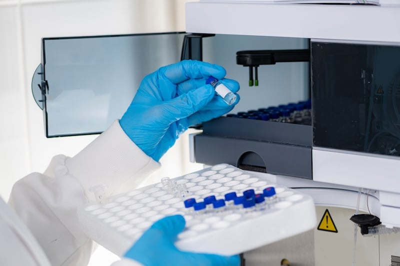 Clinical trial, using HPLC. The image depicts a lab setting involved in clinical research or drug development, specifically showing a person handling samples in vials, possibly as part of a liquid chromatography process. Samples were prepared using Type 1 ultrapure water